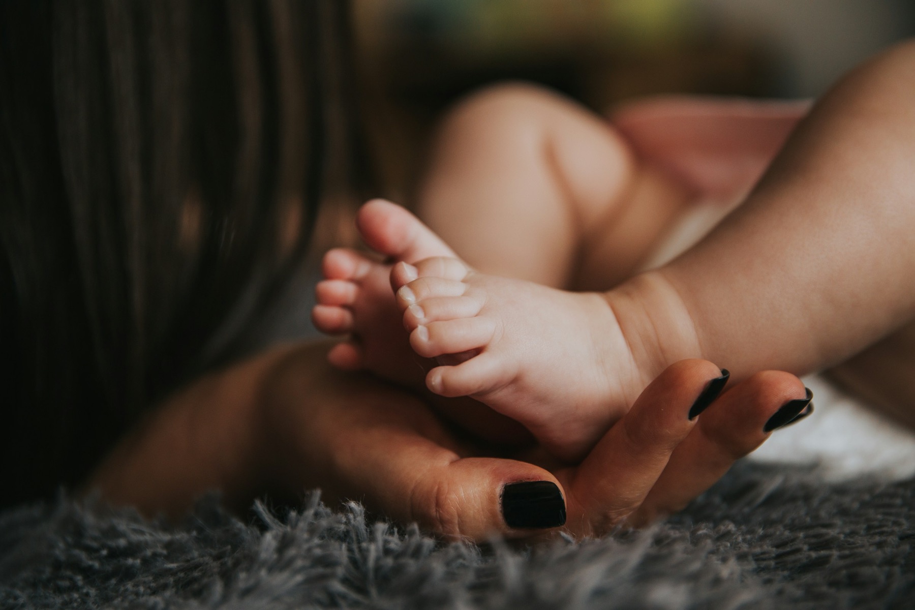 Symbolbild: Babyfüsse in den Händen einer Mutter