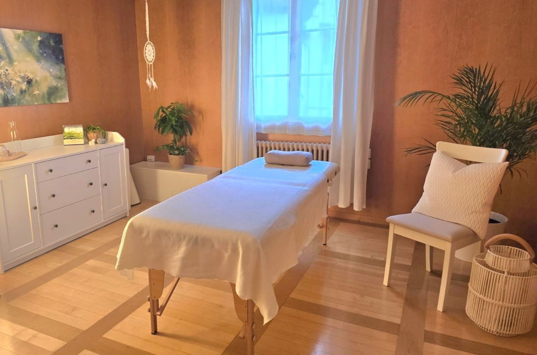 Behandlungsraum mit Massageliege, Stuhl und Fenster